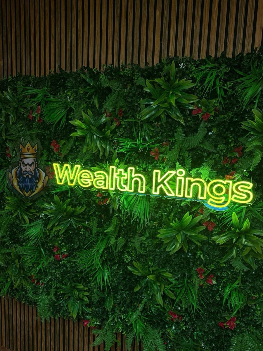 LED sign van Wealth Kings met UV-geprint logo op een groene wand